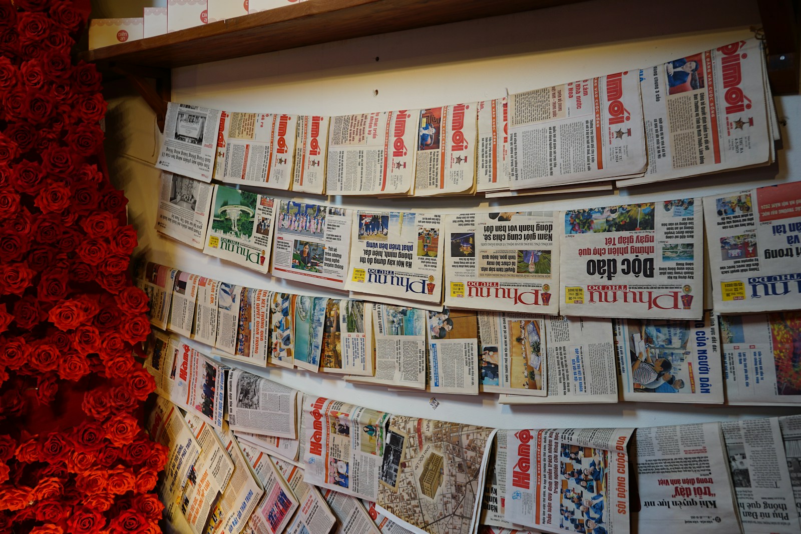 Newspapers pinned to a wall, side view.